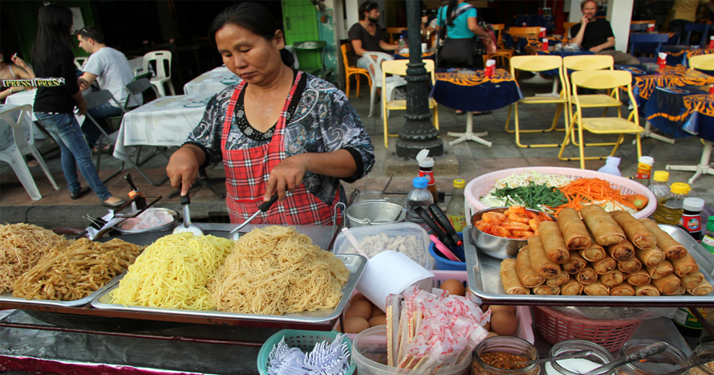 تصویری از زنی تایلندی در حال پخت غذاهای خیابانی تایلندی